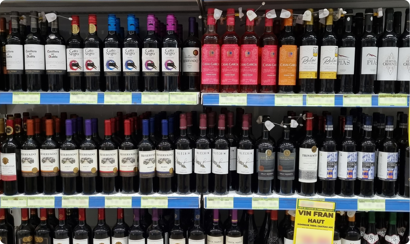 Imagem mostra uma prateleira de supermercado com vários vinhos com rátulos e garrafas semelhantes. Apenas uma marca se destaca pela embalagem, mostrando que o design pode influenciar na escolha e na percepção de valor da empresa.