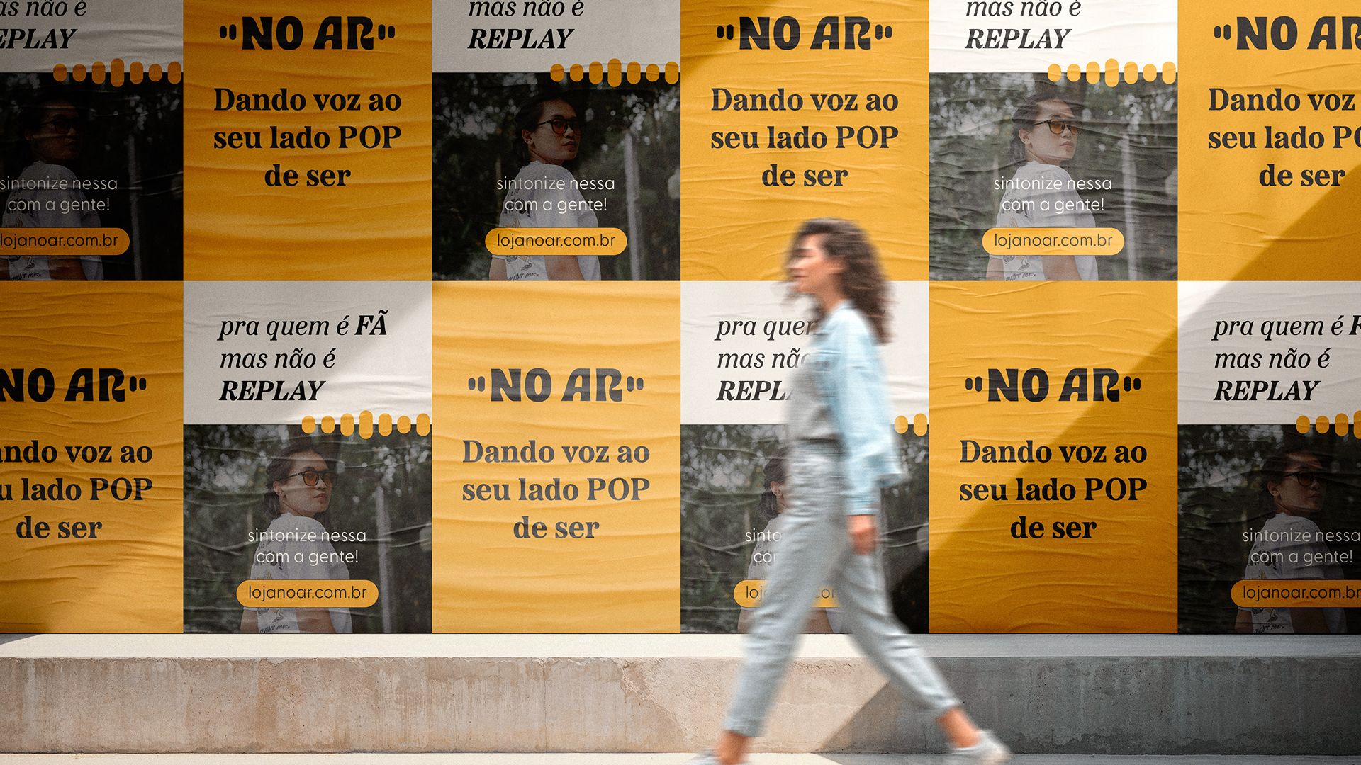 Posters na rua com foto de produto, logo e frases: "dando voz ao seu lado pop de ser" e "pra quem é FÃ, mas não é Replay".