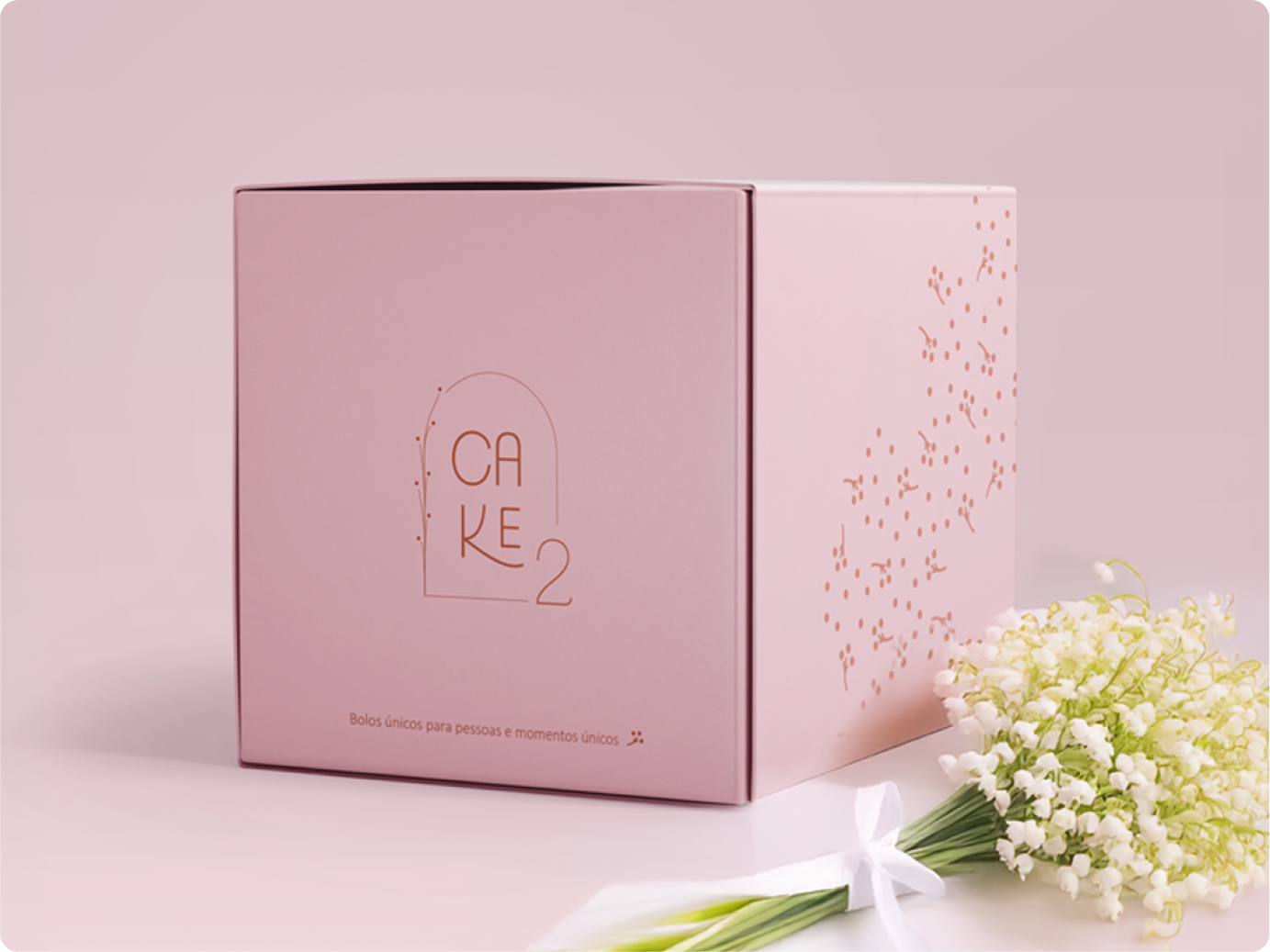 Embalagem quadrada na cor rosa claro com a logo da Cake 2 confeitaria e frase "bolos únicos para momentos únicos".